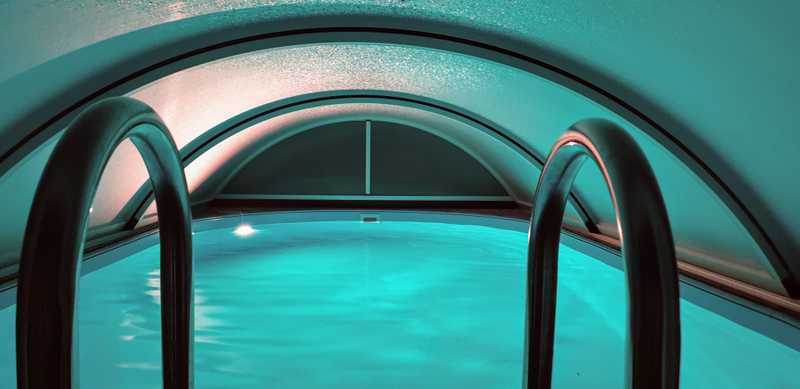 Pool mit blauer Beleuchtung mit Dach von innen bei Nacht